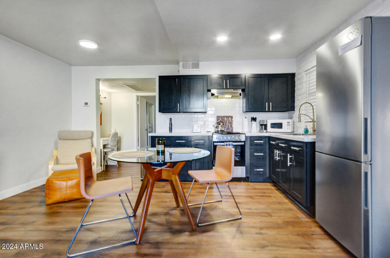 3737 East Turney Avenue, Unit 116 Phoenix, AZ 85018 - Photo 8 of 24 a kitchen with stainless steel appliances kitchen island granite countertop a refrigerator a stove a sink dishwasher and a dining table with wooden floor