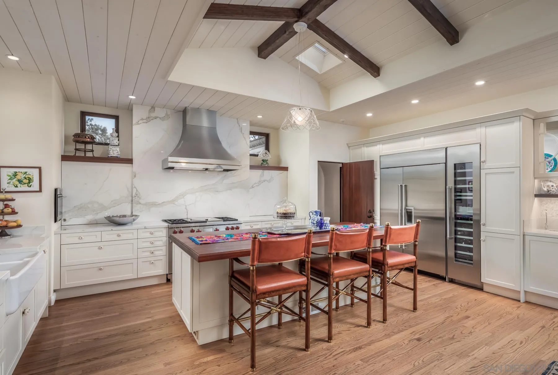 545 Rimini Road Del Mar, CA 92014 - Photo 12 of 34 a kitchen with stainless steel appliances a table chairs and a refrigerator