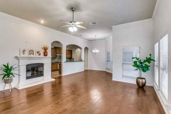 a view of an empty room with a potted plant a fireplace and wooden floor