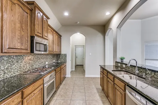 a large kitchen with granite countertop a sink and a stove top oven