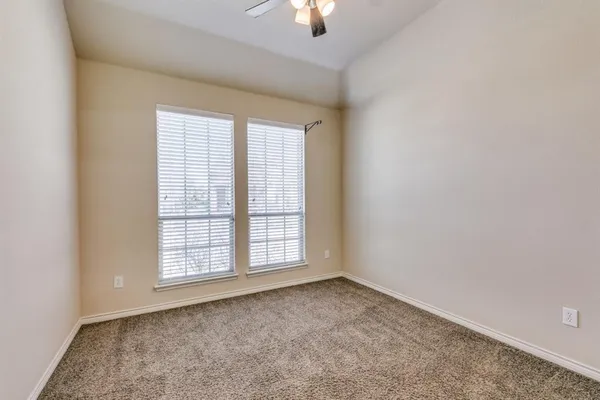 an empty room with chandelier fan and windows