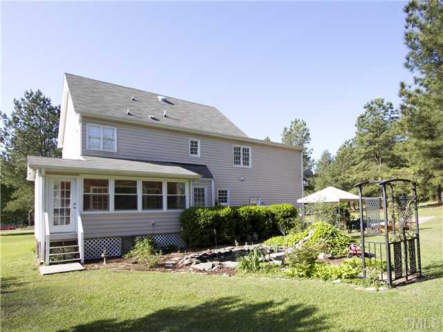3521 Catlett Farm Road Wake Forest, NC 27587 - Photo 19 of 25 Back of home showing sunroom, koi pond, patio with canopy, and a deck (behind shrubs).