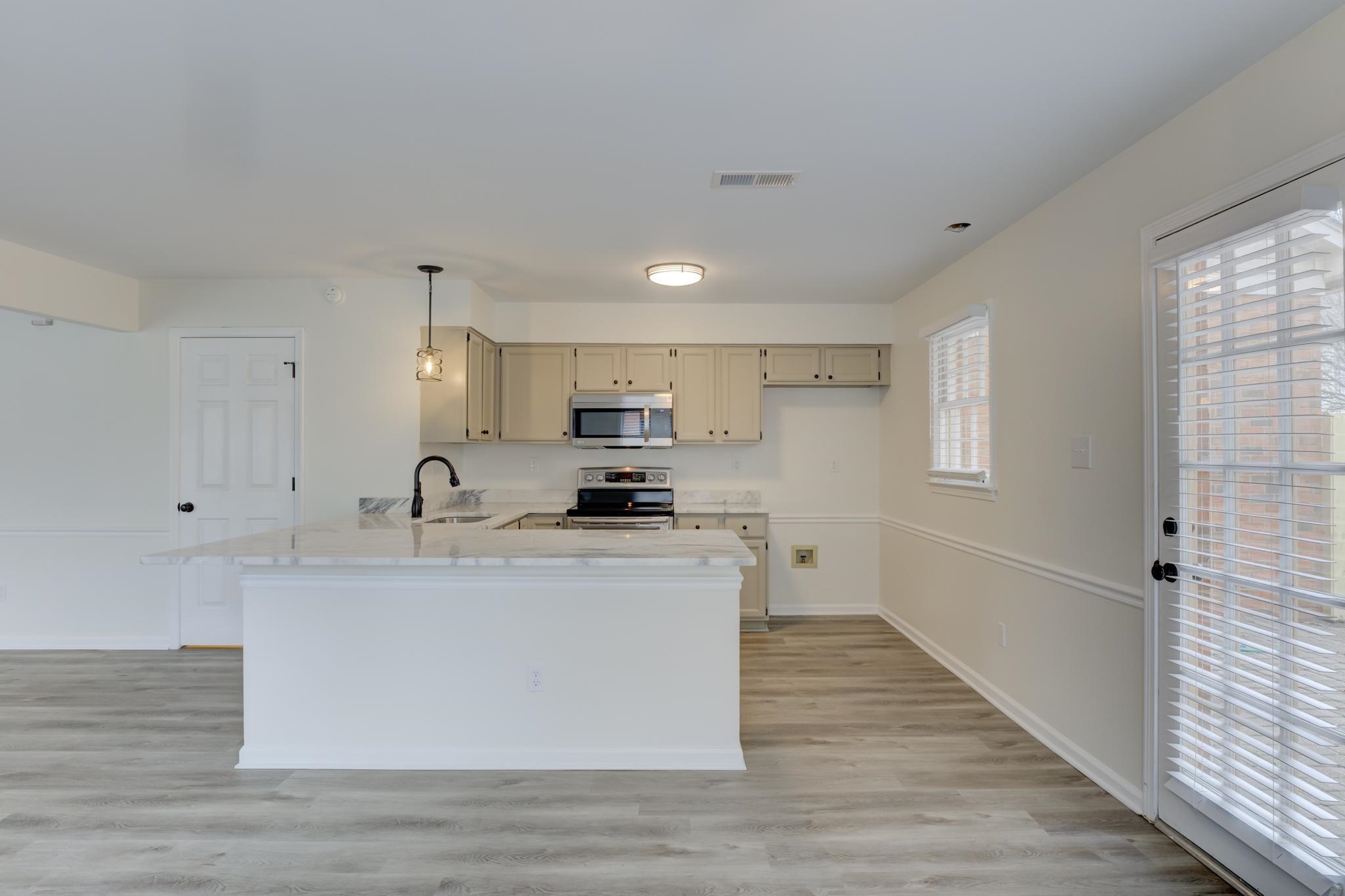 3997 Sawgrass Drive Memphis, TN 38125 - Photo 8 of 24 a large white kitchen with stainless steel appliances granite countertop a stove a sink a refrigerator white cabinets and wooden floor