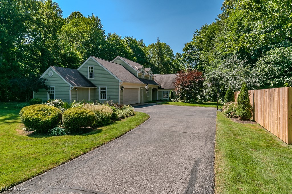 View of property exterior featuring a garage and asphalt driveway