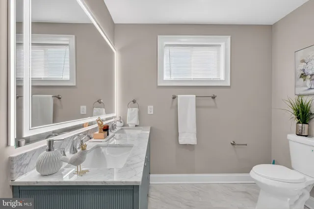 a bathroom with a granite countertop sink a mirror and a toilet