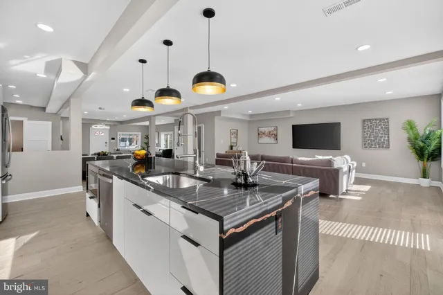 a kitchen with stainless steel appliances granite countertop a sink a stove and a wooden floors