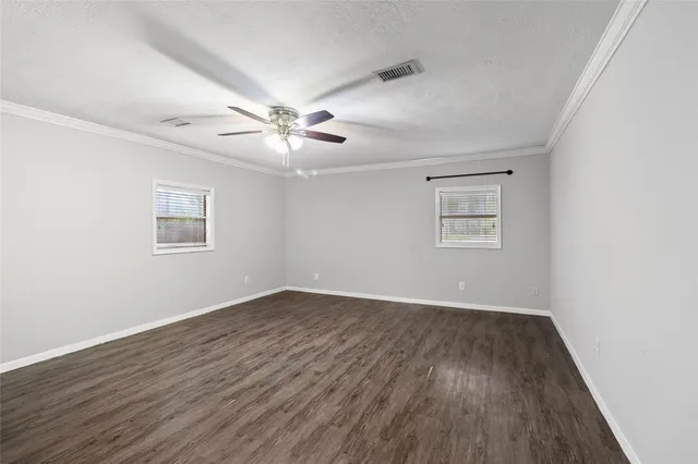 a view of an empty room with a window and wooden floor