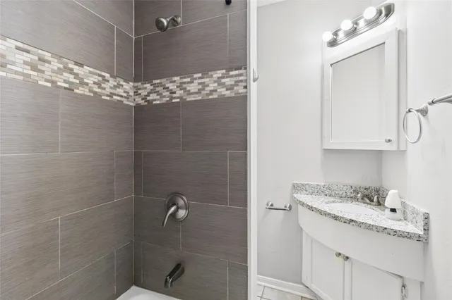a bathroom with a granite countertop shower a sink and cabinets