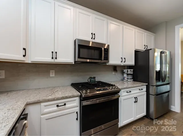 a kitchen with stainless steel appliances granite countertop white cabinets and a stove a oven with white countertops