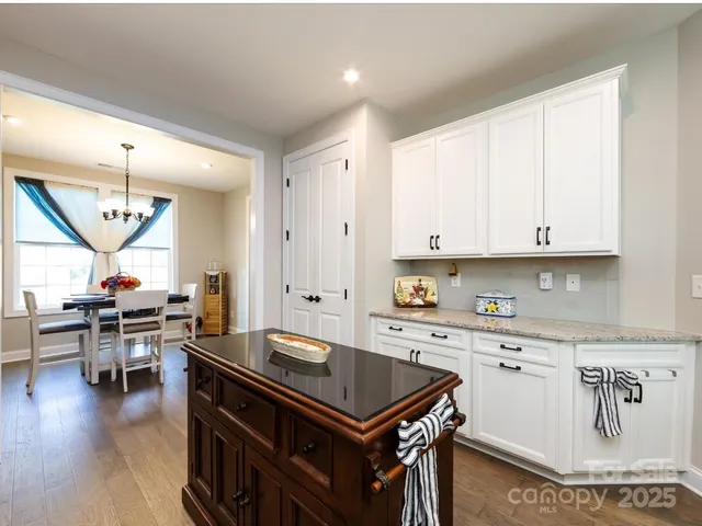 a kitchen with stainless steel appliances granite countertop a stove a sink dishwasher and a dining table with wooden floor