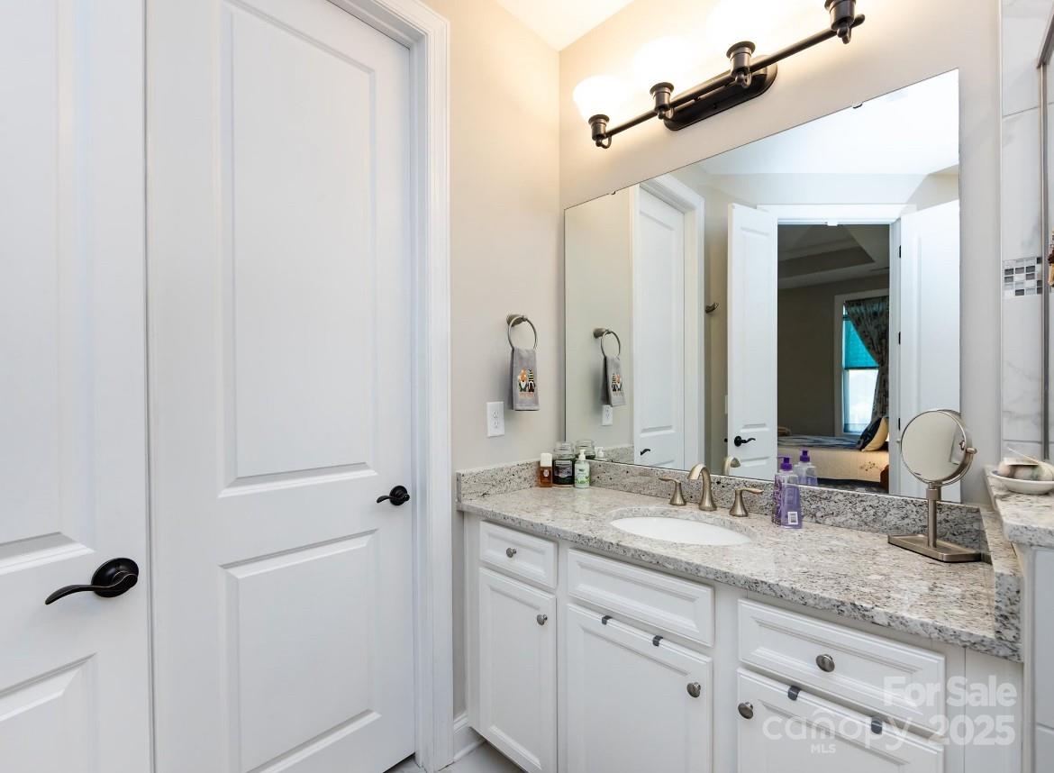 7337 Overjoyed Crossing Charlotte, NC 28215 - Photo 21 of 28 a bathroom with a granite countertop sink and a mirror