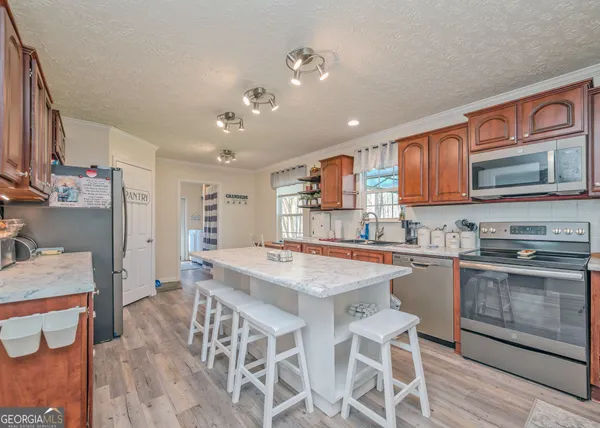 a kitchen with stainless steel appliances granite countertop a stove top oven a sink counter space and chairs