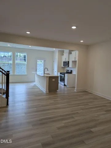 a kitchen with kitchen island granite countertop a sink wooden floor and stainless steel appliances