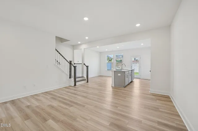 a kitchen with stainless steel appliances a stove a sink a refrigerator white cabinets and wooden floor