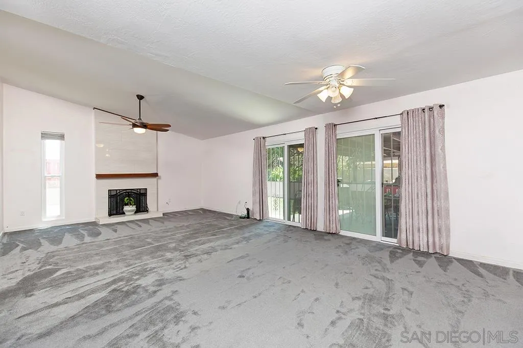 10941 Del Rio Road Spring Valley, CA 91978 - Photo 2 of 19 a view of an empty room with chandelier fan and a fireplace
