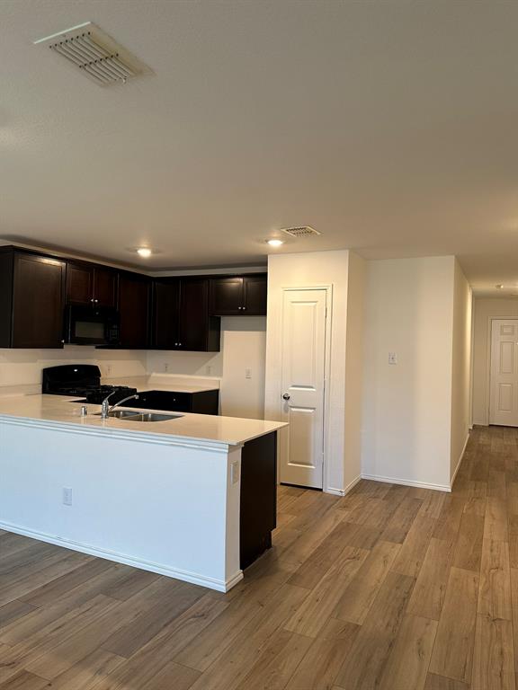 5906 Nyquist Way Forney, TX 75126 - Photo 4 of 27 Kitchen with light wood-type flooring, black appliances, light countertops, a peninsula, and recessed lighting