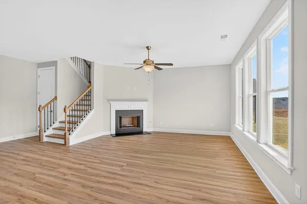 a view of an empty room with wooden floor fireplace and a window