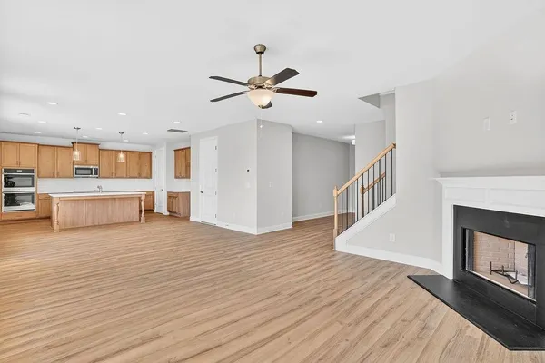 a view of a kitchen and an empty room with wooden floor a fireplace