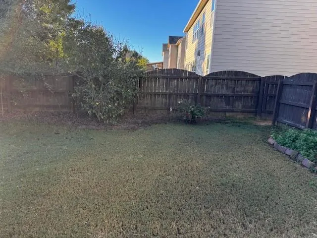 a view of a house with a small yard and wooden fence