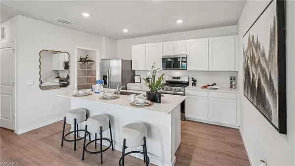 a kitchen with stainless steel appliances a sink a stove a refrigerator cabinets and a dining table with wooden floor