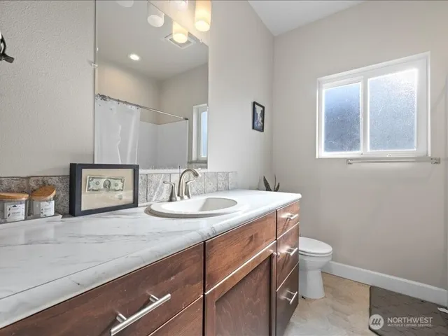 a bathroom with a granite countertop sink and a toilet