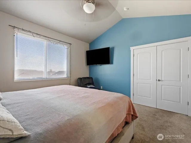 a bedroom with a bed and a flat tv screen on dresser