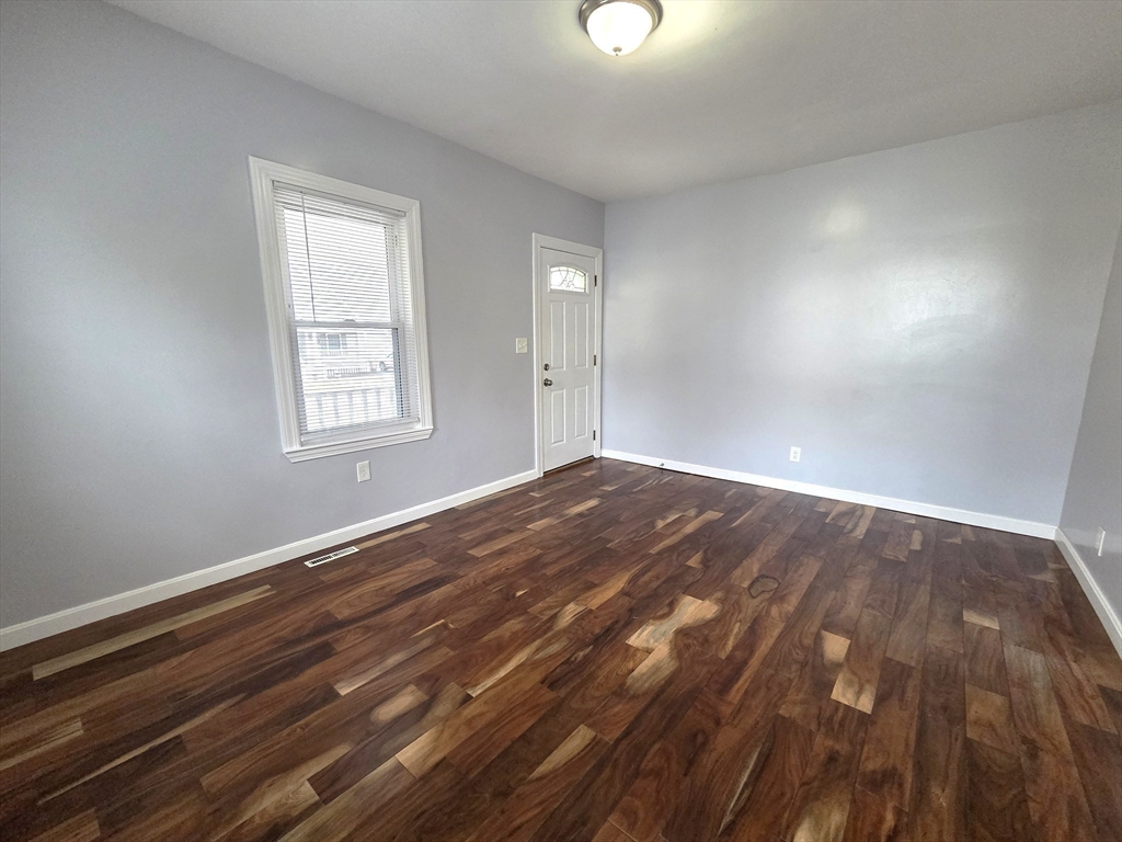 69 Pratt Street, Unit 1 Avon, MA 02322 - Photo 4 of 18 an empty room with wooden floor windows and cabinet