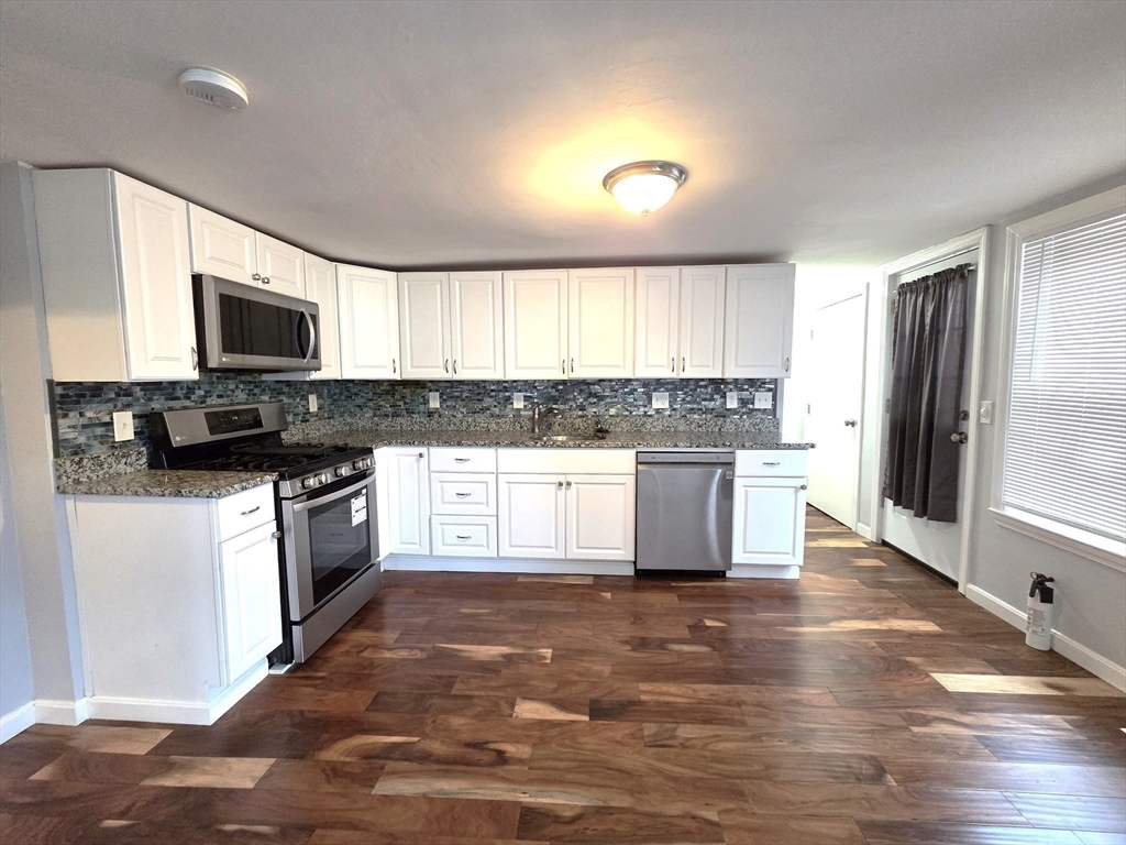 69 Pratt Street, Unit 1 Avon, MA 02322 - Photo 8 of 18 a kitchen with stainless steel appliances granite countertop a stove top oven a sink dishwasher a refrigerator and a microwave