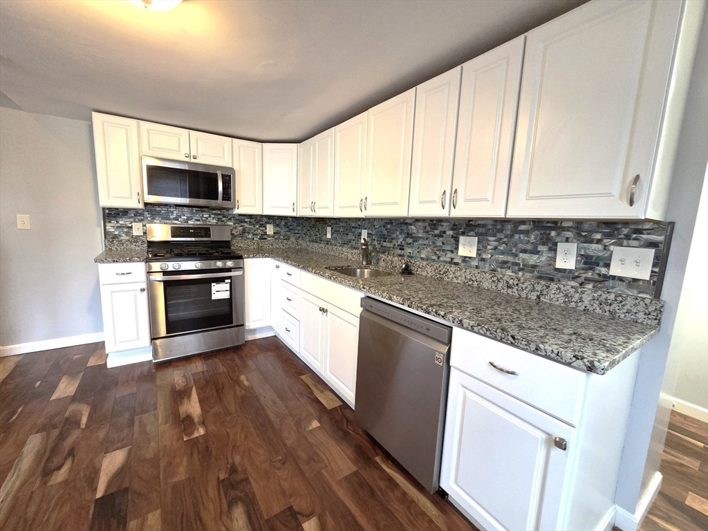 69 Pratt Street, Unit 1 Avon, MA 02322 - Photo 9 of 18 a kitchen with stainless steel appliances granite countertop a stove a sink and a microwave
