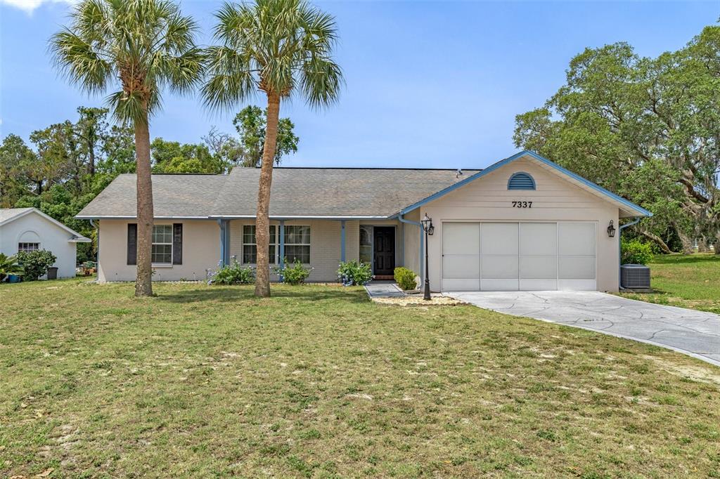 7337 Glasgow Road Weeki Wachee, FL 34613 - Photo 1 of 1 a front view of a house with a yard and garage