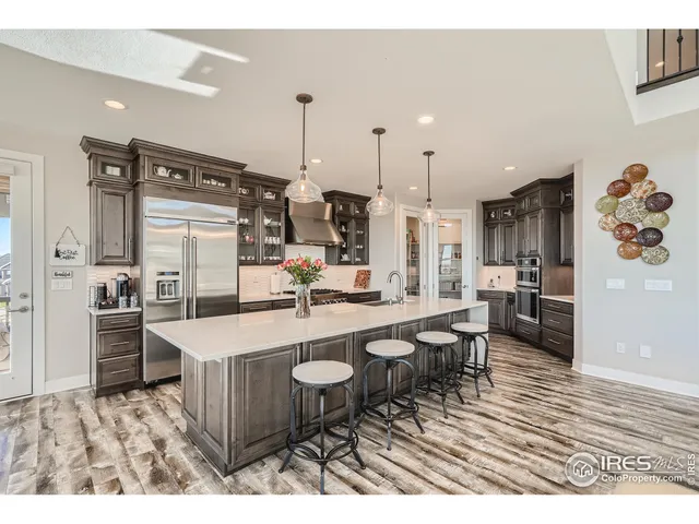 a open kitchen with white cabinets a sink dishwasher and a stove with wooden floor