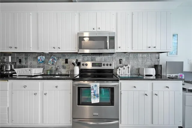 a kitchen with granite countertop white cabinets and white appliances