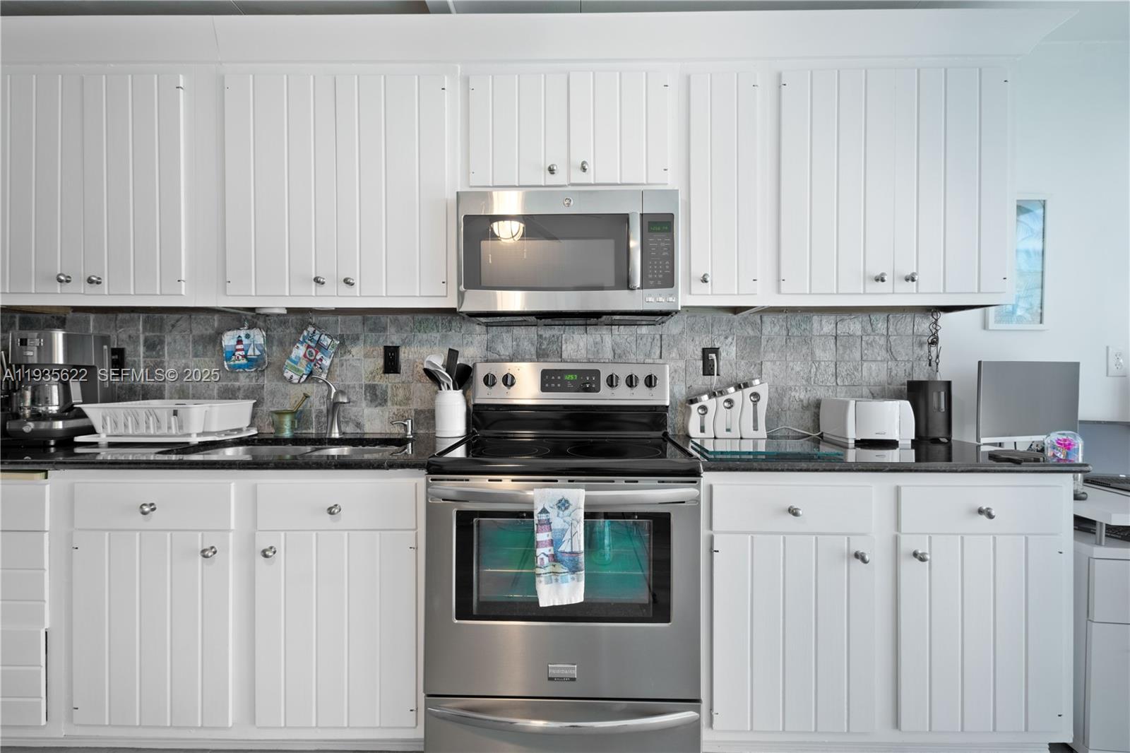 1361 Overseas Highway, Unit E11 Marathon, FL 33050 - Photo 16 of 29 a kitchen with granite countertop white cabinets and white appliances