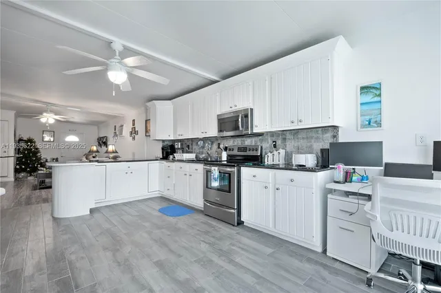 a kitchen with stainless steel appliances white cabinets a sink a stove a refrigerator and white cabinets