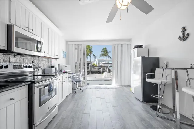 a kitchen with stainless steel appliances a stove top oven a refrigerator a sink and dishwasher with white cabinets