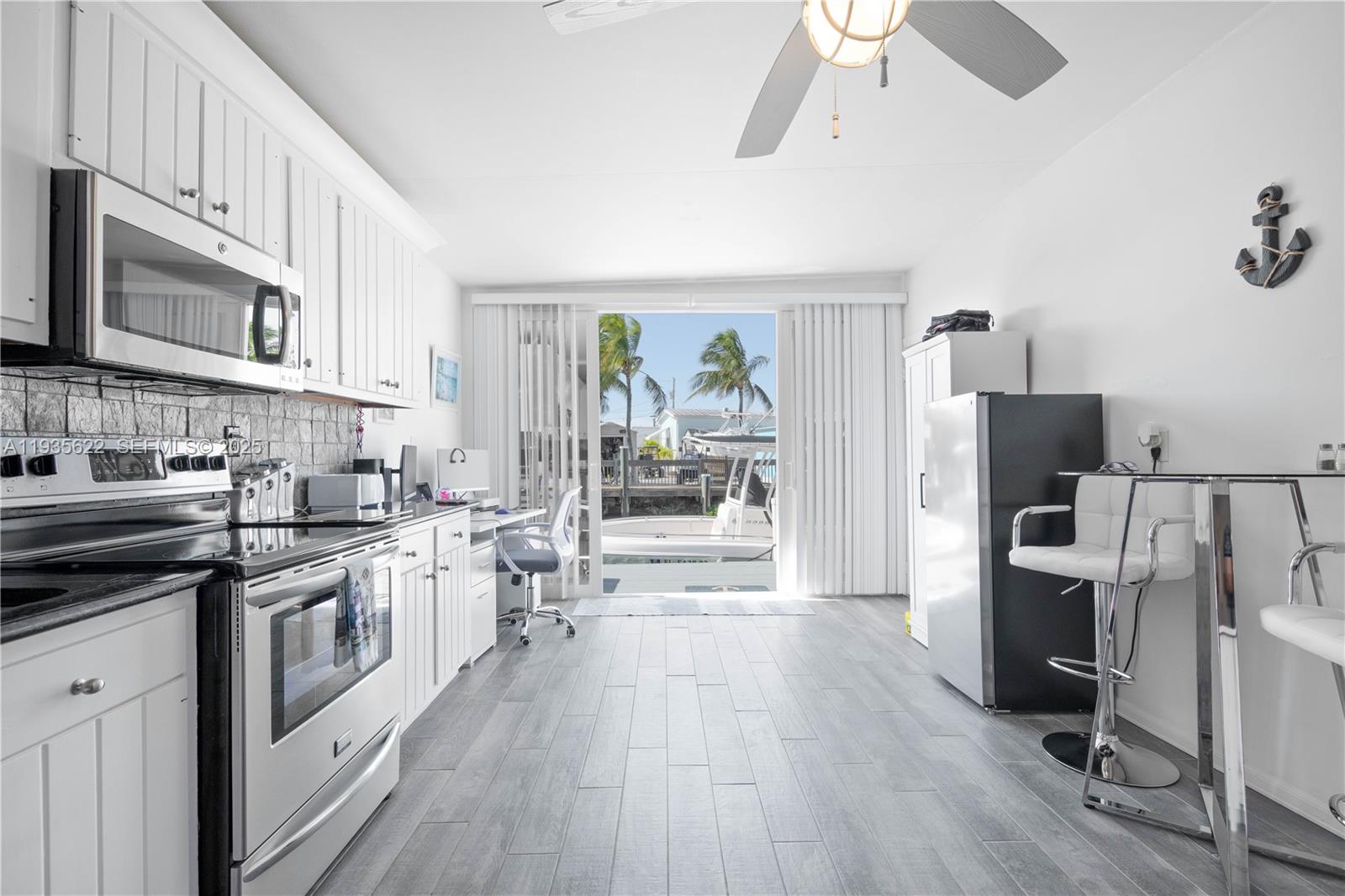 1361 Overseas Highway, Unit E11 Marathon, FL 33050 - Photo 19 of 29 a kitchen with stainless steel appliances a stove top oven a refrigerator a sink and dishwasher with white cabinets
