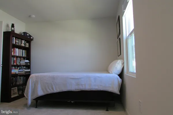 a bedroom with a bed and a potted plant on the dresser