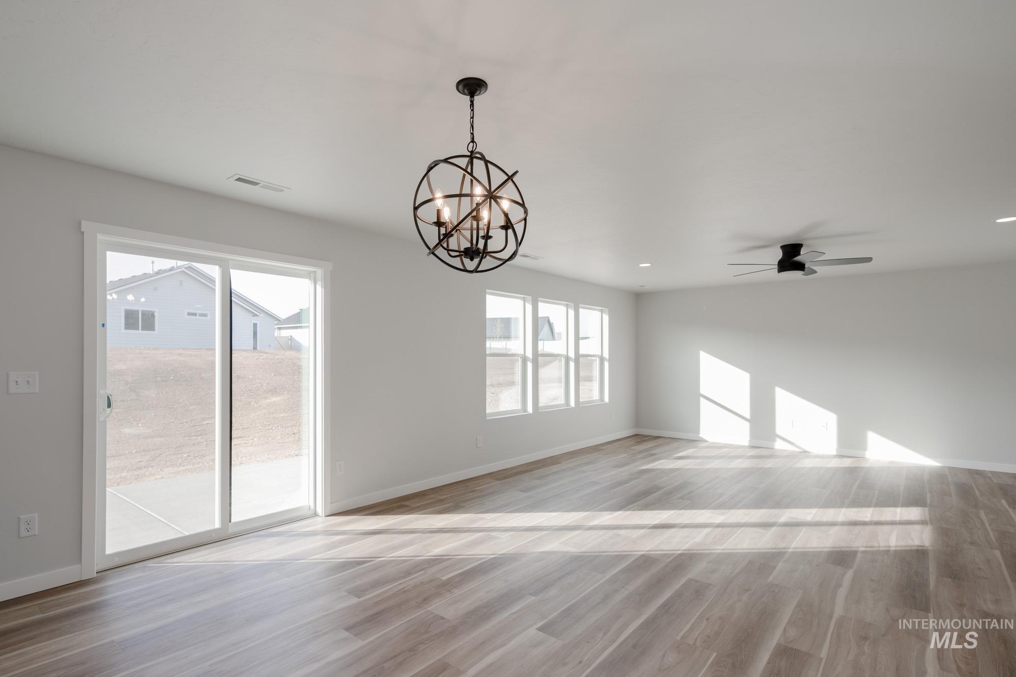1613 Covington Street Middleton, ID 83644 - Photo 8 of 25 Empty room featuring light wood-style flooring, a chandelier, and ceiling fan