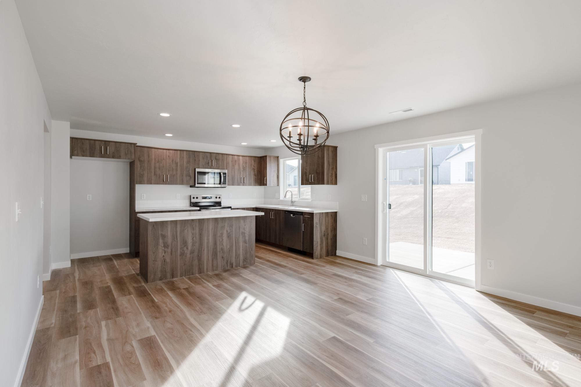 1613 Covington Street Middleton, ID 83644 - Photo 9 of 25 Kitchen featuring hanging lights, light countertops, a kitchen island, light wood finished floors, and stainless steel appliances