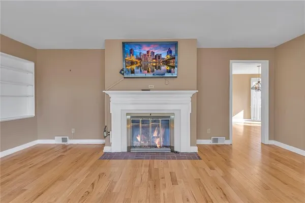 a view of an empty room with wooden floor and a fireplace