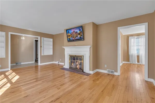 a view of a livingroom with wooden floor and a fireplace