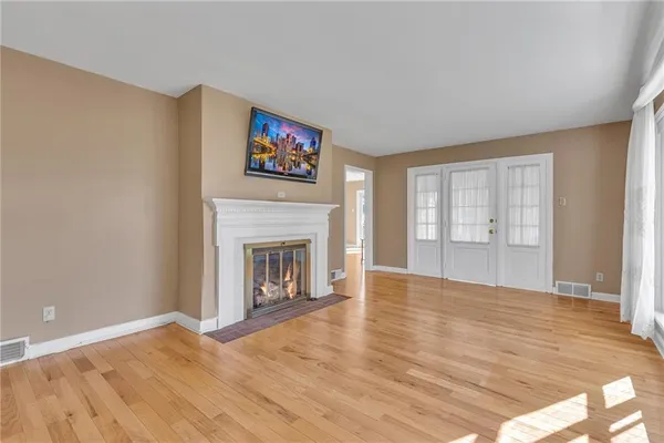 a view of empty room with wooden floor and fireplace