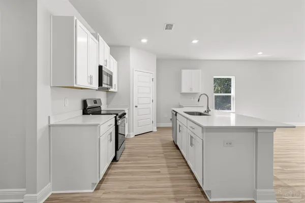 a large kitchen with stainless steel appliances granite countertop a lot of counter space and wooden floors