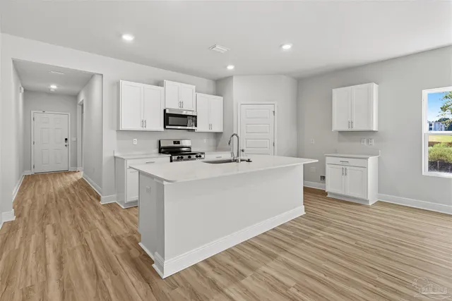a open kitchen with kitchen island a sink dishwasher stove and white cabinets with wooden floor