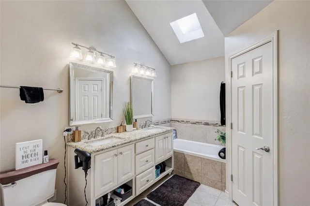 a spacious bathroom with a double vanity sink a mirror and a bathtub