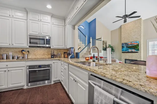 a kitchen with granite countertop a sink stainless steel appliances and white cabinets