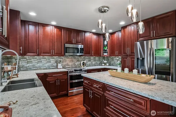 a kitchen with stainless steel appliances granite countertop wooden cabinets a sink and dishwasher