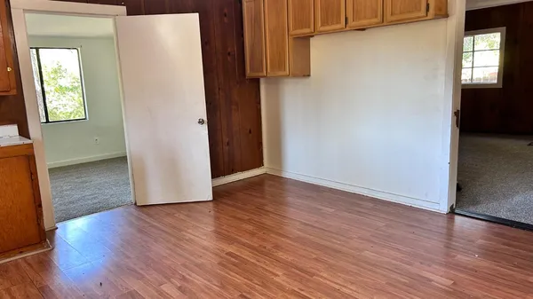 an empty room with wooden floor and windows