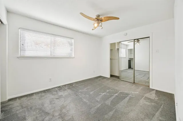 an empty room with a chandelier fan and closet