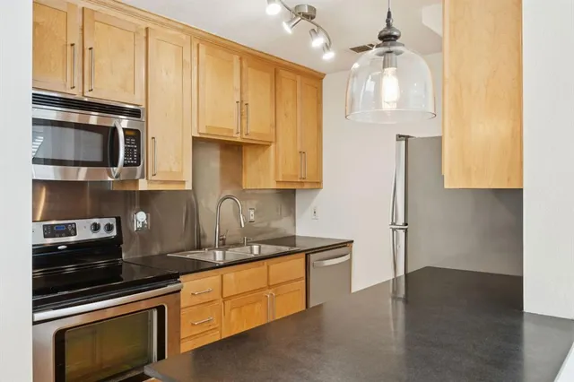 a kitchen with stainless steel appliances granite countertop a refrigerator and a stove top oven